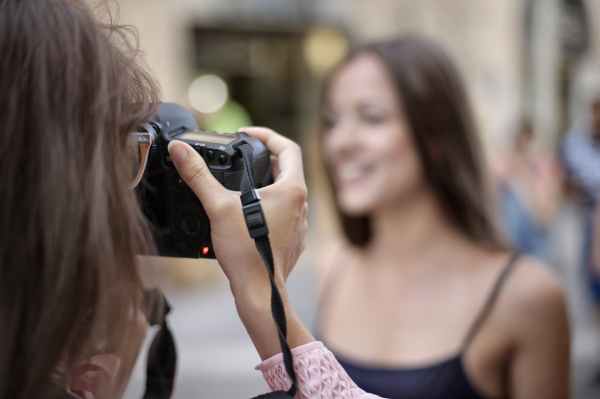 Looking over the shoulder of a photographer as they take a picture of another person who is blurred due to the distance.