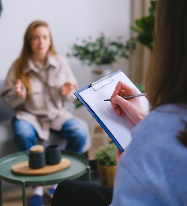 Looking over the shoulder of a person taking notes while another person talks.